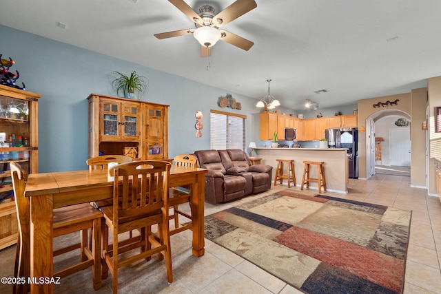 dining space featuring light tile patterned floors, arched walkways, ceiling fan with notable chandelier, and visible vents