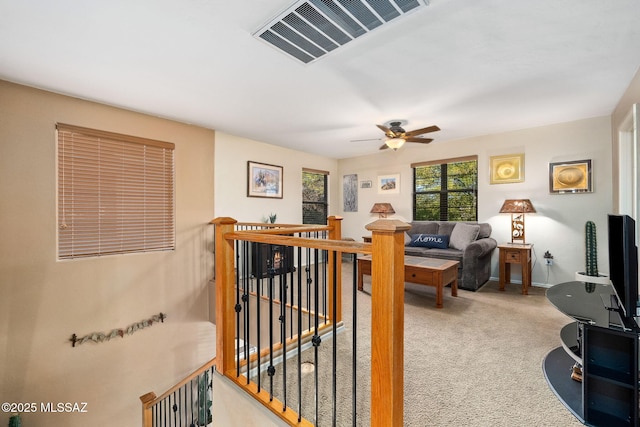 living area featuring visible vents, carpet flooring, baseboards, and ceiling fan