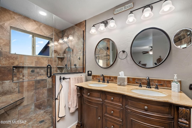 full bathroom with double vanity, a sink, a ceiling fan, and tiled shower