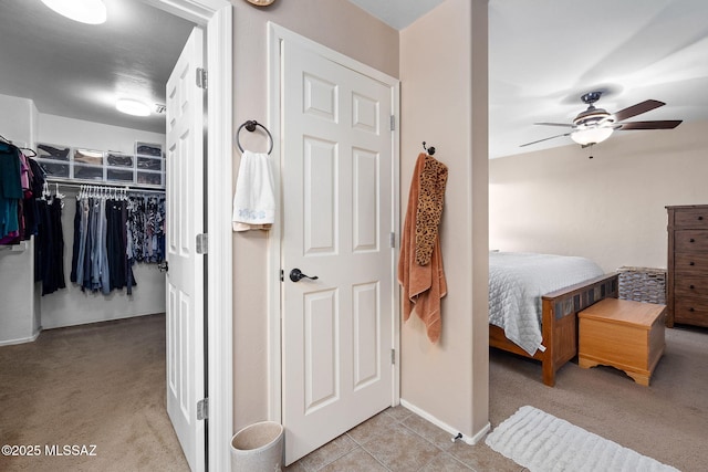 bedroom featuring a walk in closet, baseboards, tile patterned floors, a closet, and carpet flooring