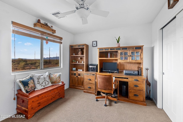 carpeted office space featuring baseboards, ceiling fan, and visible vents