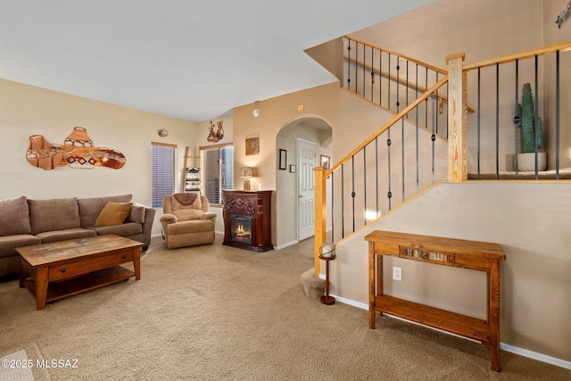 carpeted living area with baseboards, arched walkways, and stairway