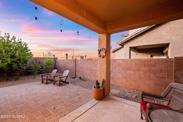 patio terrace at dusk featuring a fenced backyard