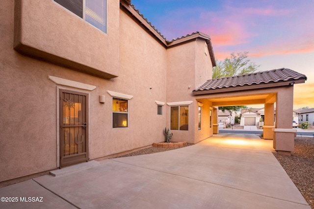 rear view of property featuring a tiled roof, a patio, and stucco siding