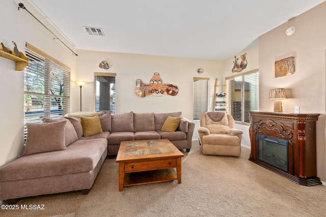 living area featuring visible vents, plenty of natural light, carpet, and a glass covered fireplace