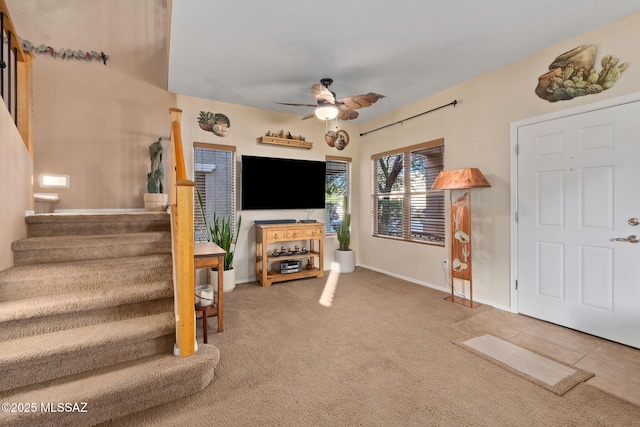 carpeted entryway featuring stairway, baseboards, and ceiling fan