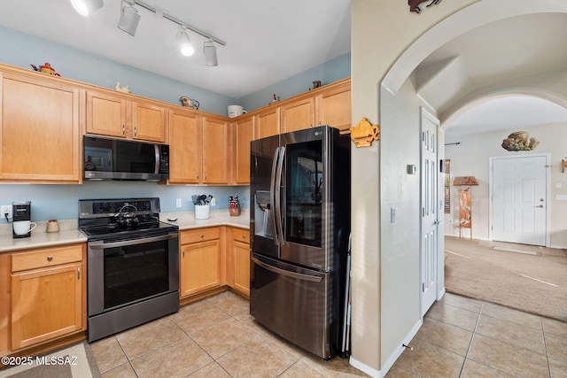 kitchen with light countertops, arched walkways, appliances with stainless steel finishes, and light tile patterned floors