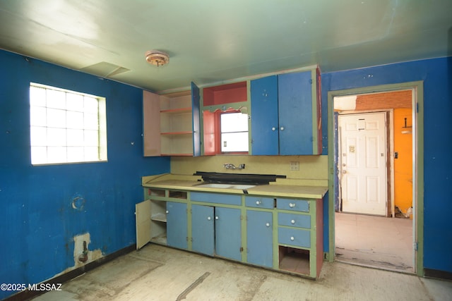 kitchen featuring light countertops, open shelves, a sink, and a healthy amount of sunlight
