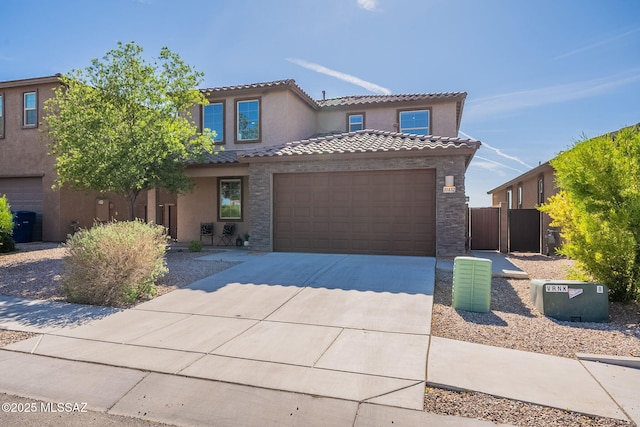 mediterranean / spanish-style house featuring driveway, a tile roof, fence, an attached garage, and stucco siding