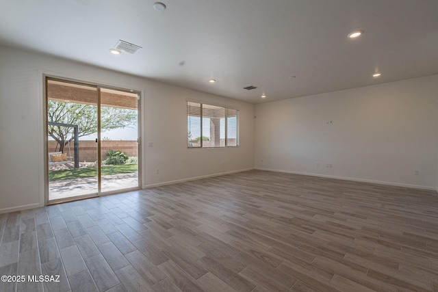 empty room featuring baseboards, wood finished floors, and visible vents