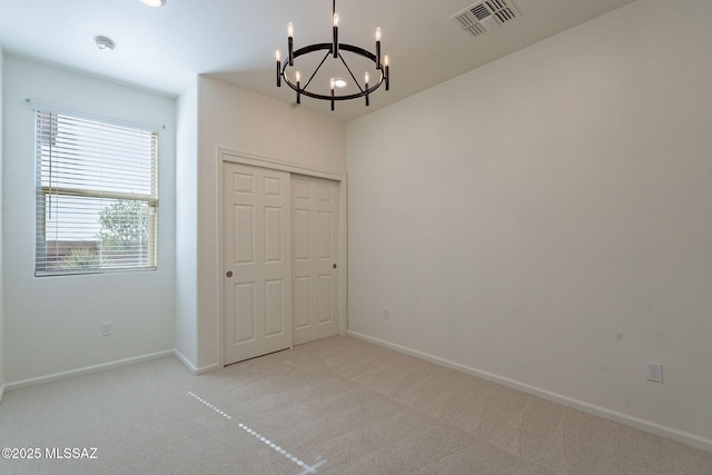 unfurnished dining area with baseboards, visible vents, carpet, and a notable chandelier