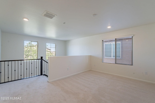spare room with baseboards, light carpet, recessed lighting, and visible vents