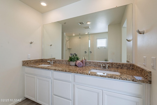 full bathroom with double vanity, visible vents, a shower stall, and a sink