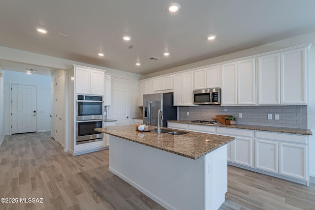 kitchen featuring visible vents, a sink, light wood finished floors, and stainless steel appliances