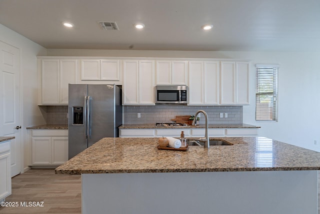 kitchen featuring visible vents, a sink, light wood finished floors, and stainless steel appliances