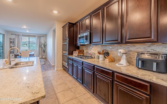 10199 S Pantano Knolls Dr, Vail, AZ 85641 - kitchen with light stone countertops, appliances with stainless steel finishes, a sink, decorative backsplash, and light tile patterned floors