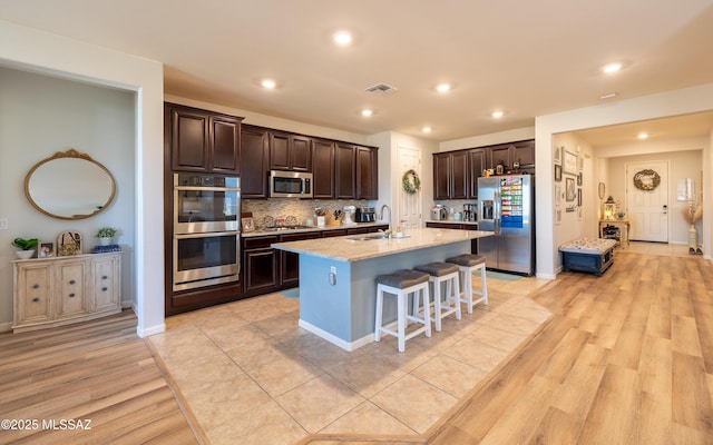 10199 S Pantano Knolls Dr, Vail, AZ 85641 - kitchen featuring visible vents, appliances with stainless steel finishes, a breakfast bar area, and dark brown cabinets