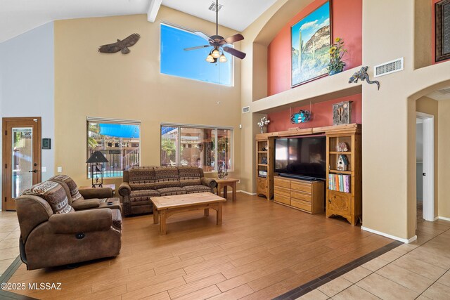 9949 N Blue Crossing Way, Tucson, AZ 85743 - living room with high vaulted ceiling, beam ceiling, arched walkways, a ceiling fan, and wood finished floors