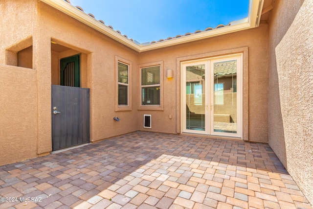 view of exterior entry featuring a gate, stucco siding, and a patio area