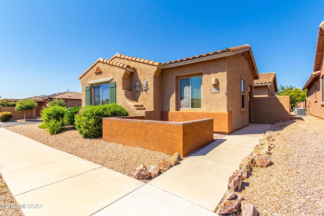view of front of property with central AC unit, stucco siding, fence private yard, and a tile roof