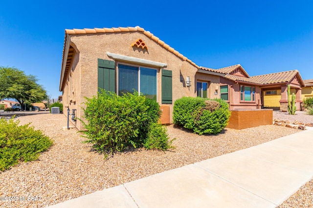 view of front of property featuring stucco siding, central AC, and a tile roof
