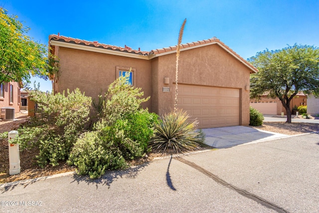 view of front of property with stucco siding, cooling unit, concrete driveway, and a garage