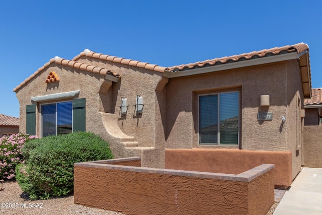 view of front facade featuring a tiled roof and stucco siding