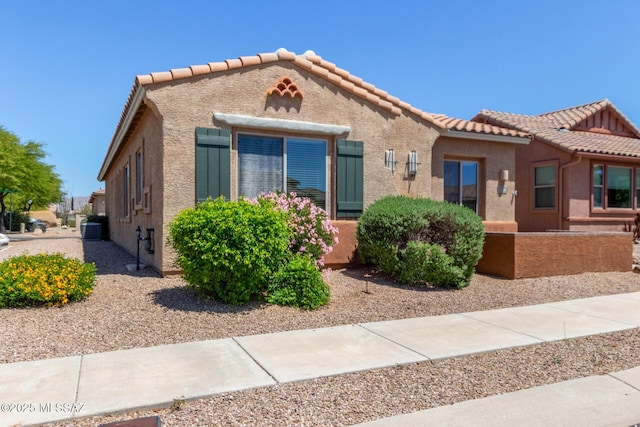 view of front of home with stucco siding, a tiled roof, and cooling unit