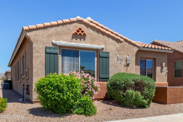 view of front of house with central AC unit, stucco siding, and a tiled roof