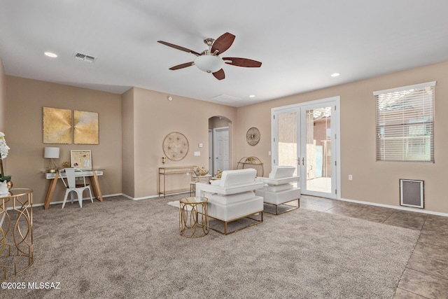 tiled living room with visible vents, arched walkways, a ceiling fan, and a healthy amount of sunlight