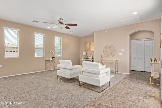 living area featuring arched walkways, ceiling fan, visible vents, and baseboards