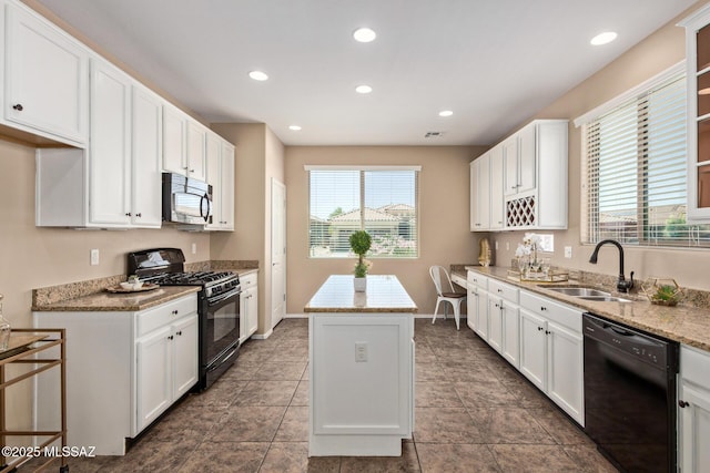 kitchen with white cabinets, a sink, black appliances, and a center island