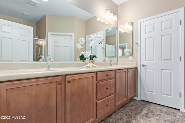 full bathroom with double vanity, a shower with shower door, a sink, and visible vents