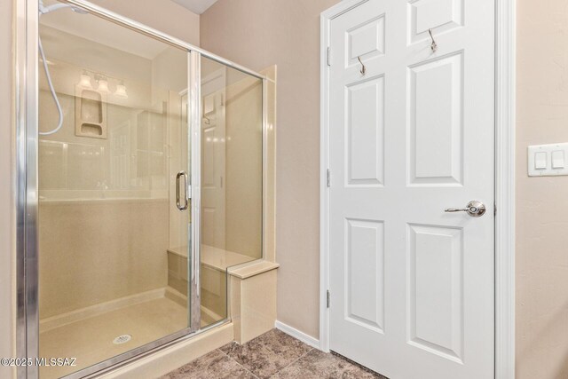 full bath featuring baseboards, tile patterned flooring, and a stall shower