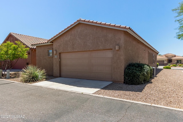 view of home's exterior featuring a garage, stucco siding, driveway, and a tiled roof