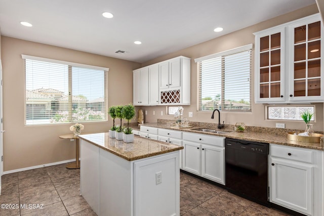 kitchen featuring visible vents, glass insert cabinets, black dishwasher, a center island, and a sink