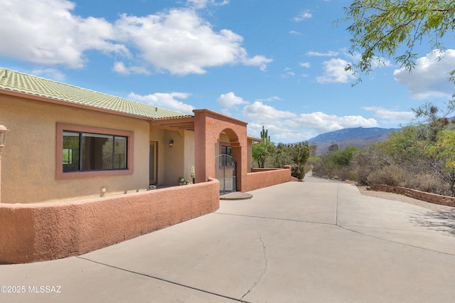 exterior space featuring a mountain view, a patio, stucco siding, a tile roof, and concrete driveway