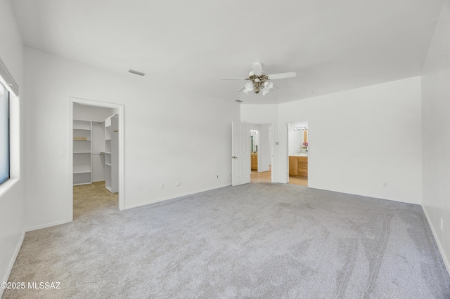 12471 E Speedway Blvd, Tucson, AZ 85748 - unfurnished bedroom with light carpet, a spacious closet, ceiling fan, and ensuite bathroom