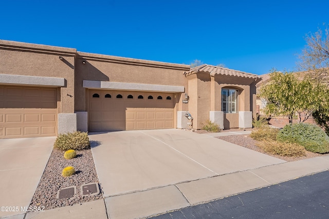 view of front of house featuring stucco siding, an attached garage, driveway, and a tile roof