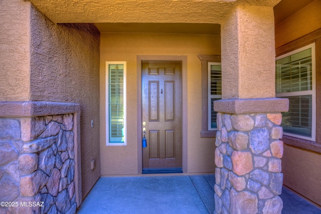doorway to property with stone siding and stucco siding