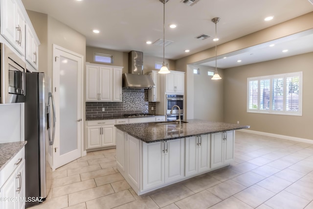 kitchen featuring a sink, stainless steel appliances, wall chimney range hood, visible vents, and decorative backsplash