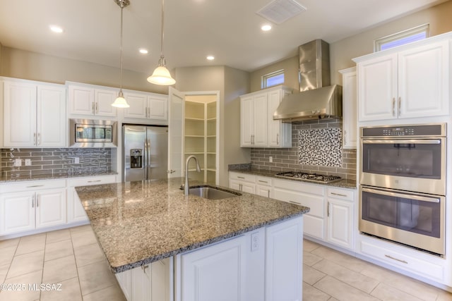 kitchen featuring a sink, stainless steel appliances, visible vents, wall chimney exhaust hood, and backsplash