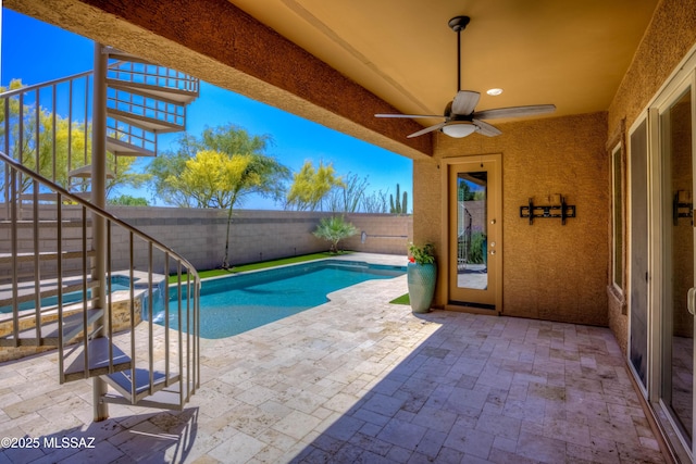 view of pool featuring stairs, a patio, a fenced backyard, a fenced in pool, and a ceiling fan