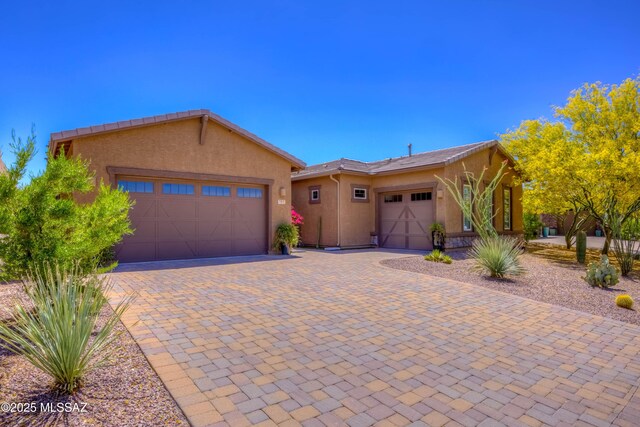 view of front facade featuring stucco siding, an attached garage, and decorative driveway