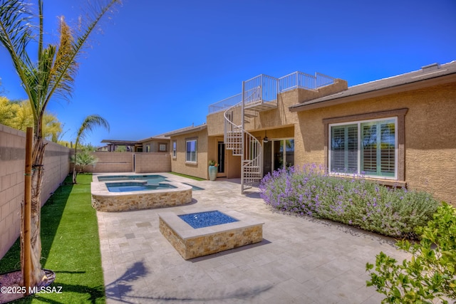 exterior space featuring a fire pit, an in ground hot tub, a fenced backyard, and stairs