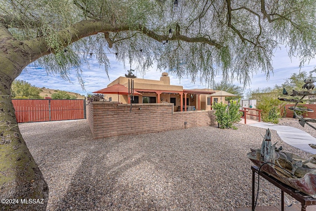 rear view of property featuring fence private yard, a chimney, a gate, and stucco siding