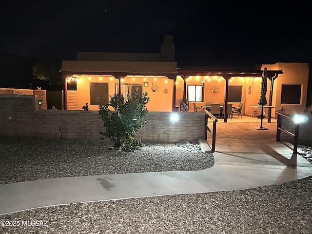view of front of home with a patio, stucco siding, and fence