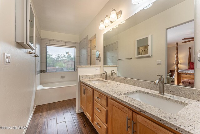 ensuite bathroom with a sink, a bath, double vanity, and wood finished floors