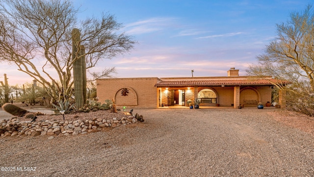 900 N Camino Del Codorniz, Tucson, AZ 85749 - view of front of home featuring a tile roof, a chimney, covered porch, and brick siding