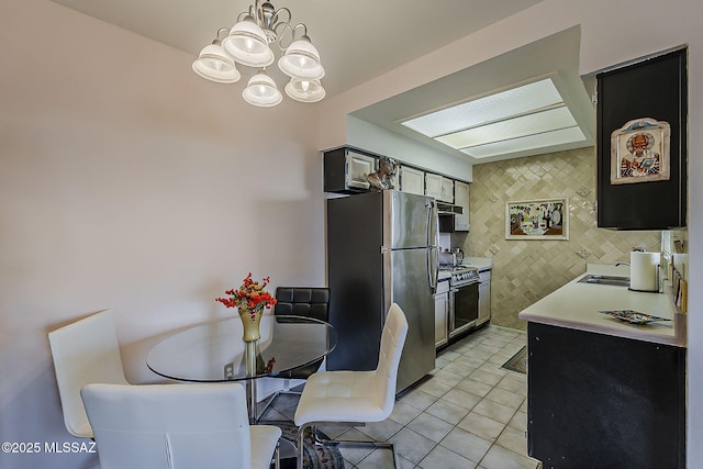 kitchen with light countertops, a chandelier, range with gas stovetop, freestanding refrigerator, and light tile patterned floors